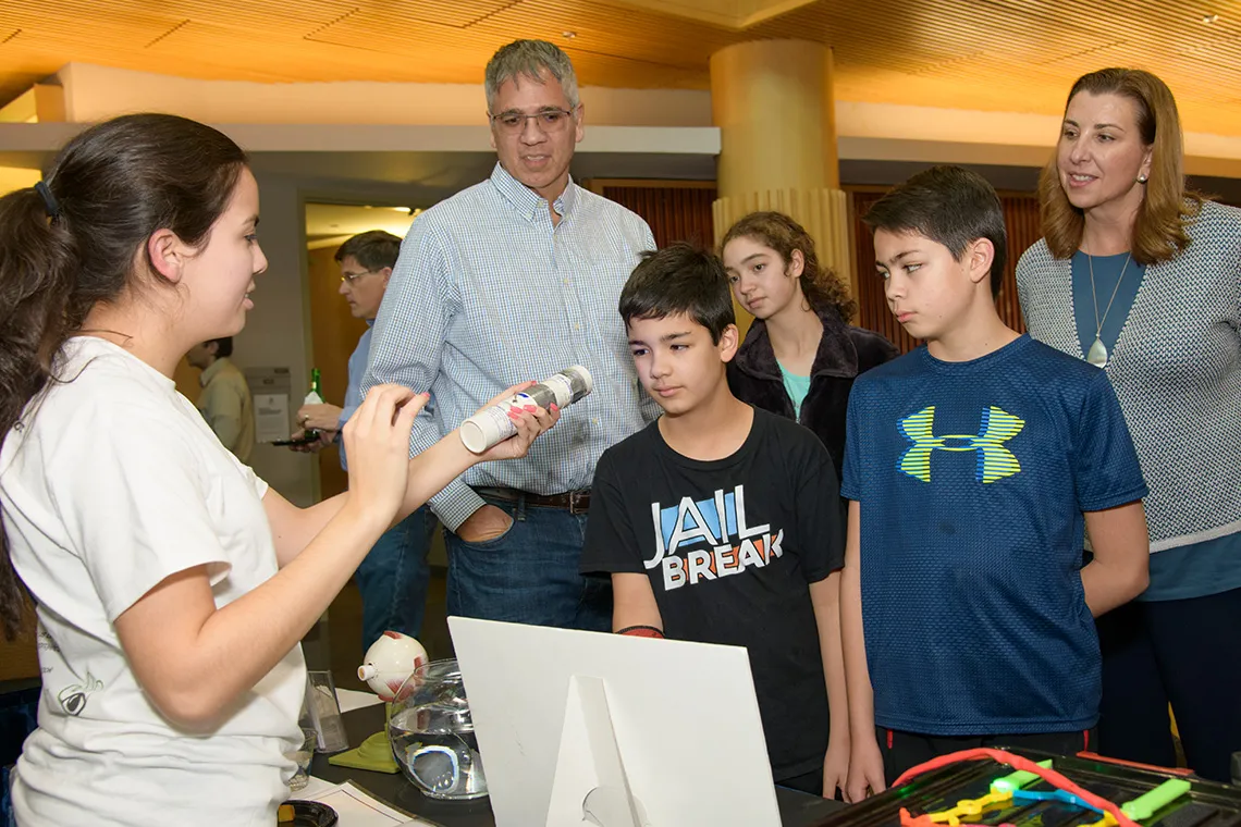 A group of people exploring a science tabling event.