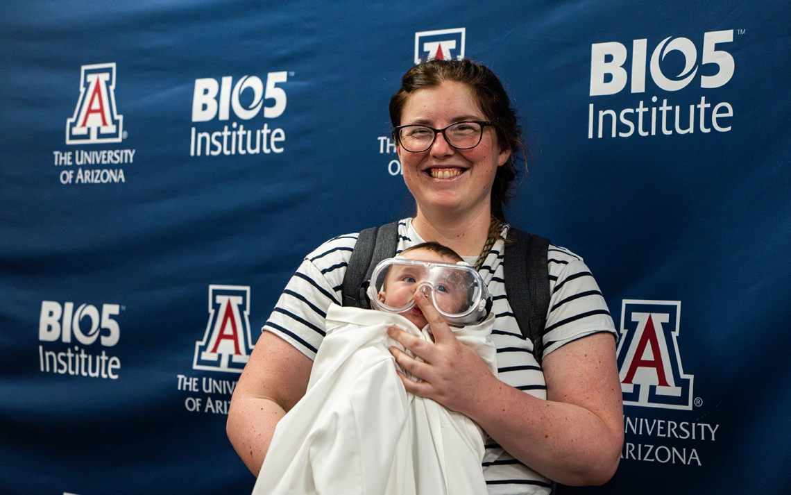 A mother and her baby who is dressed in a lab coat and safety goggles