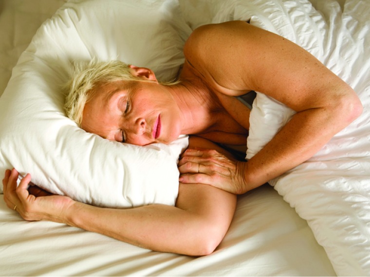 Woman sleeping in a bed with a white pillow and white bedding