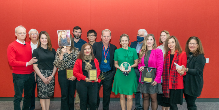 Winners of 2021 staff awards in front of a red wall.