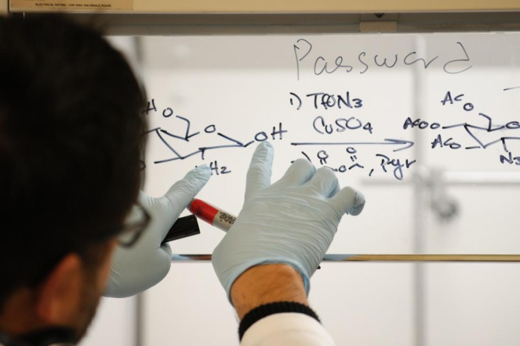 Researcher writing chemical equation on glass with dry erase marker